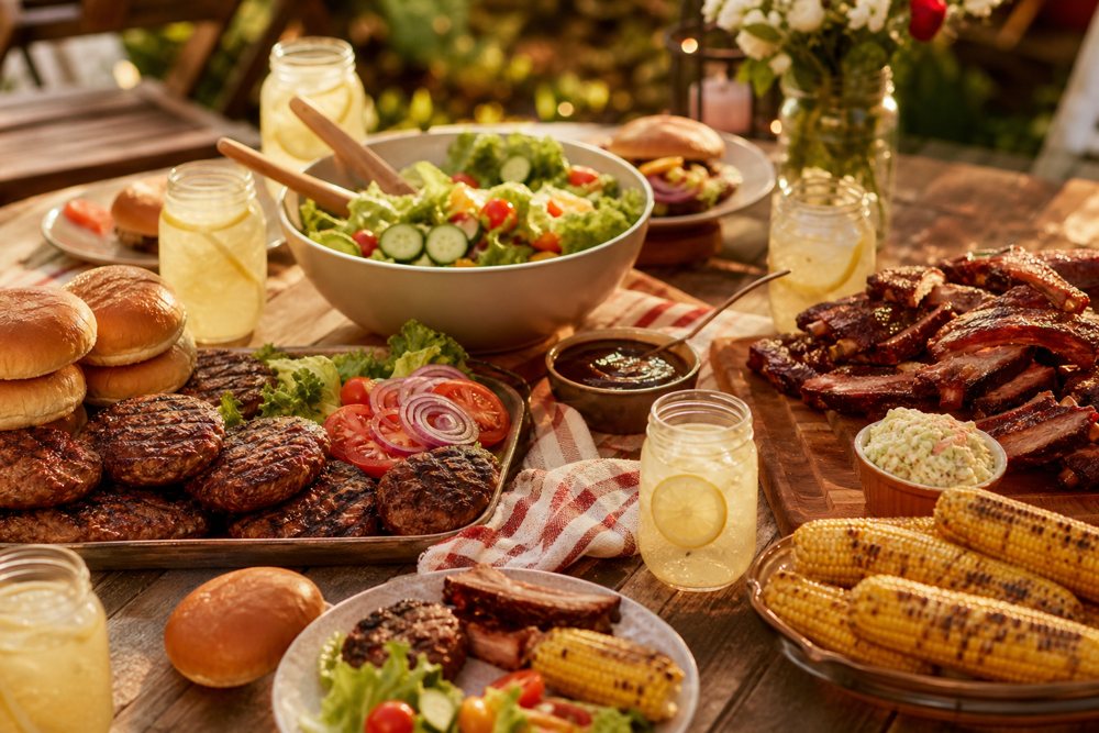 A backyard Father's Day cookout lunch spread for five — grilled burgers, smoked ribs, corn, salad and lemonade